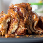 cinnamon,bun,drizzled,with,topping,and,garnished,with,pecans.,cut