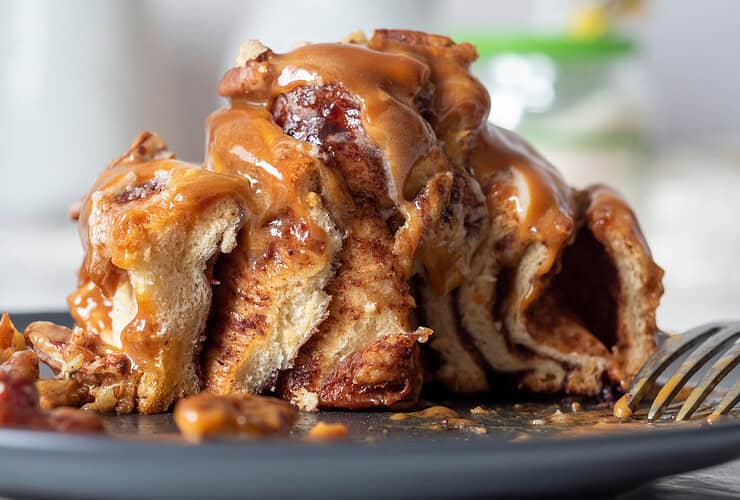 cinnamon,bun,drizzled,with,topping,and,garnished,with,pecans.,cut