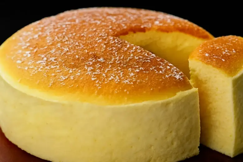 Bolo nuvem japonês fofinho, com cobertura dourada e textura leve, servido com fatia cortada