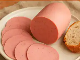 Mortadela caseira fatiada em prato branco com pão artesanal ao lado