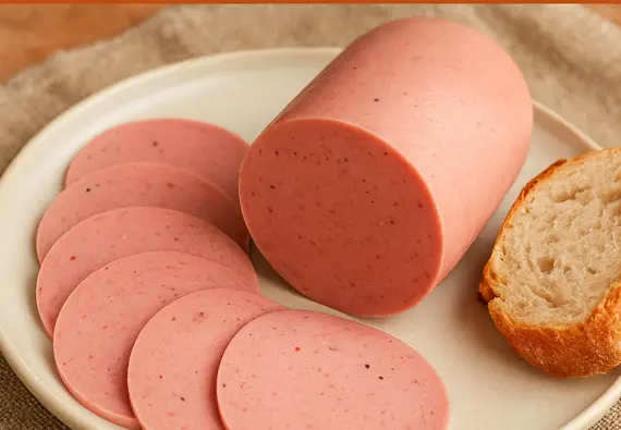 Mortadela caseira fatiada em prato branco com pão artesanal ao lado